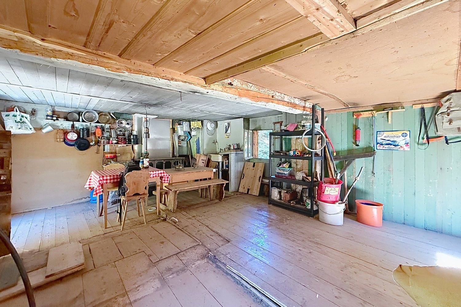 Seconde pièce du mayen avec table, bancs et plafond partiellement repris en planches claires.